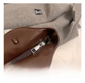 Macro view of silver metal zipper detail and stitching on dark brown leather tote bag