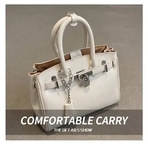 Macro detail of the sturdy rolled leather handles and metal clasp on this beige handbag