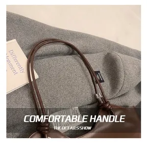 Detail of hand-knotted leather handle and silver metal hardware on dark brown tote bag