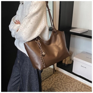 Detail of dark brown tote bag showing the unique knotted shoulder strap and woven accessory