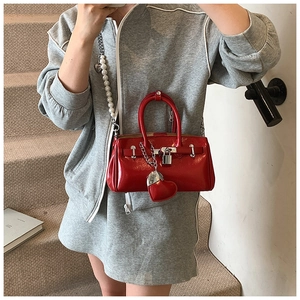 Detail of red patent leather handbag with silver padlock and unique beaded shoulder strap