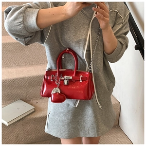 Detail of red glossy mini bag with metal lock, chain strap and heart charm