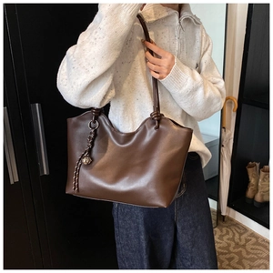 Close-up of caramel faux leather tote bag showing knot detail and metal ball charm