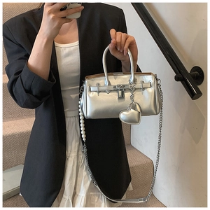 Detail of silver metallic handbag featuring pearl chain strap and heart charm decoration