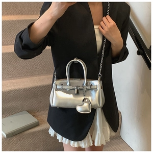 Detail of silver metallic Kelly bag with heart pendant and luxury lock closure