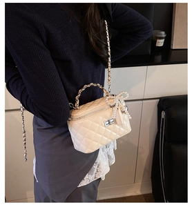 Detail van de gewatteerde boxtas met zilveren ketting en parelmoer strikhanger