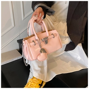 Detail view of pink patent leather Kelly bag with silver chain strap and heart charm