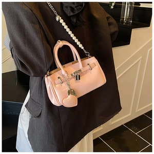 Detail of pink patent leather handbag with pearl chain strap and heart charm on a blazer