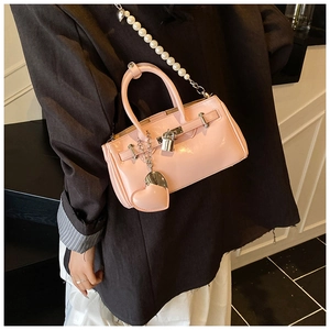 Detail view of pink patent leather handbag with pearl strap and heart pendant