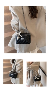 Detail van zwarte gewatteerde tas met elegante parelstrik en zilveren hartje