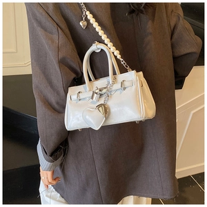 Detail of light blue mini handbag featuring pearl strap and silver heart charm decoration