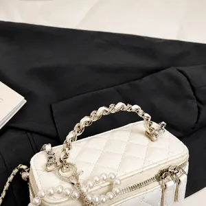 Detail van witte gewatteerde handtas met parelketting en elegant geweven handvat