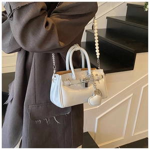 Detail of light blue glossy bag featuring decorative heart charm and pearl handle