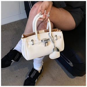 Detailed shot of a white glossy handbag featuring silver metal hardware and heart charm