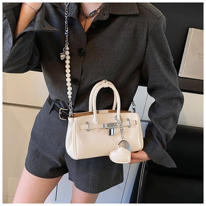 Detail of cream white leather handbag with pearl chain and silver lock for women