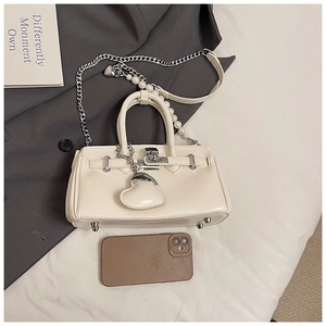Detail of off-white handbag featuring pearl chain strap and silver metal buckle closure