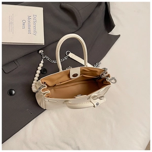 Top view of cream handbag with pearl strap and silver chain on grey blazer