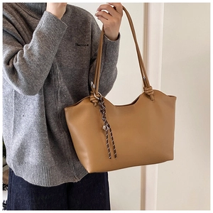 Close-up of camel leather tote bag featuring stylish woven rope pendant detail