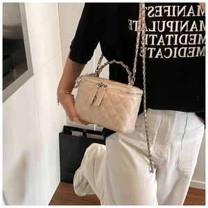 Detail van beige gewatteerde box-tas met parel handvat en metalen kettingriem