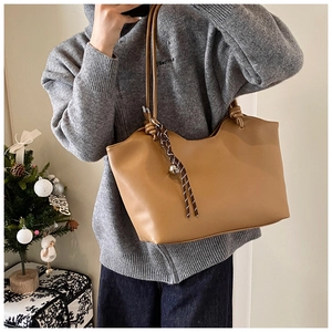 Close-up of brown leather tote bag featuring woven rope knot detail and festive holiday decor