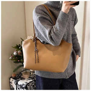 Detail of camel leather tote bag featuring metal rings and brown braided rope accent