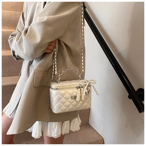Detail van witte gewatteerde vanity bag met parelstrikn en harthanger aan zilveren ketting