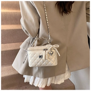 Detail van witte gewatteerde mini box tas met parelmoeren strik en zilveren hart hanger