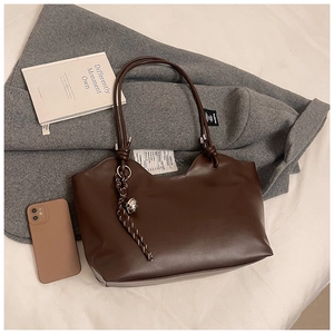 Detail of dark brown matte leather tote bag with wavy rim and woven strap accessory