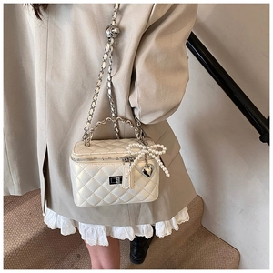 Detail van de crème gewatteerde box-tas met parelboog en zilveren ketting