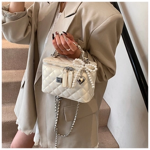Detailopname van witte gewatteerde mini box tas met parelstrik en gouden ketting