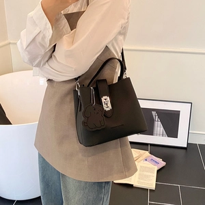Sac seau chic en cuir noir avec fermoir rotatif argenté et breloque en forme de chien