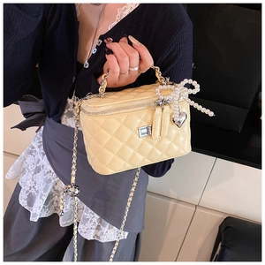 Detail van gele gewatteerde mini vanity bag met parelstrik en hartvormige hanger