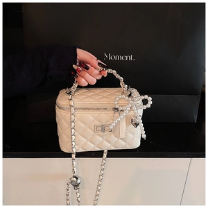 Detail van crème gewatteerde vanity case met parelstrik en zilveren kettingriem