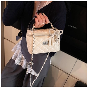 Detail van de crème gewatteerde handtas met parelstrik en zilveren hartvormige hanger