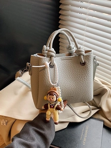 Pale green pebble leather bucket bag with knot handle and pearl doll charm detail