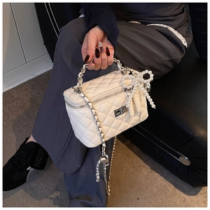 Detail van de witte gewatteerde box bag met parelmoer strikhanger en kettingriem