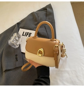Close-up of stylish two-tone leather handbag with golden horseshoe lock and top handle