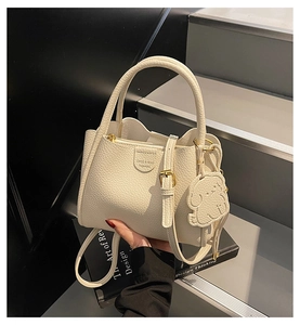 Detail of cream pebbled leather handbag with adjustable strap and cute dog charm accent