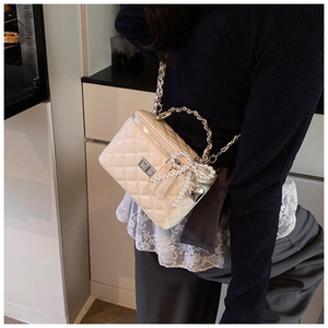 Detail van de crèmewitte gewatteerde mini-tas met parelstrik en zilveren hartjeshanger