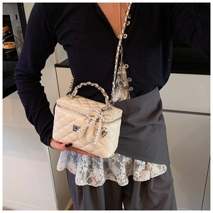 Detail van de crème gewatteerde vanity bag met parelstrikl en hartvormige metalen hanger