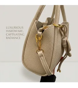 Detail of beige lychee grain leather bucket bag featuring gold hardware and drawstring