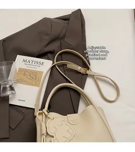 Detail of cream leather bucket bag with bear charm and adjustable strap for daily use