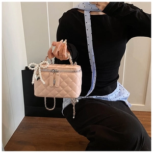 Detail van roze gewatteerde mini-tas met parelmoeren strik en zilveren ketting