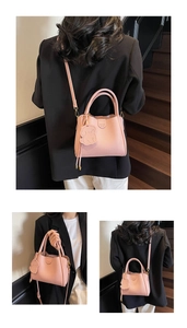 Detail of pink lychee leather handbag featuring gold logo and cute dog charm accessory