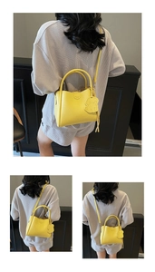 Detail of yellow lychee leather bucket bag with dog charm and detachable strap