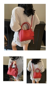 Detail view of red lychee textured bucket bag with dog pendant and embossed logo