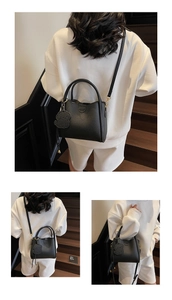 Detail of black pebbled leather bucket bag with cute dog charm and adjustable strap