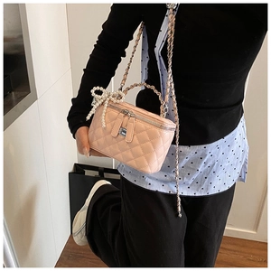 Detail van roze gewatteerde box-tas met parelmoer strik en ketting schouderriem