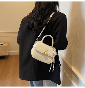 Detail of off-white crossbody bag with golden horseshoe clasp and printed silk scarf