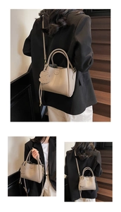 Macro view of beige lychee leather tote bag with a dog charm and adjustable strap